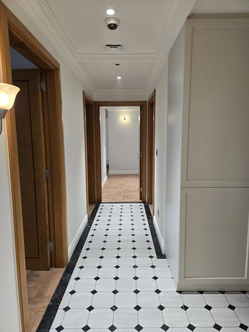 Corridor with octagon-and-dot floor tile, panelled walls and timber doors