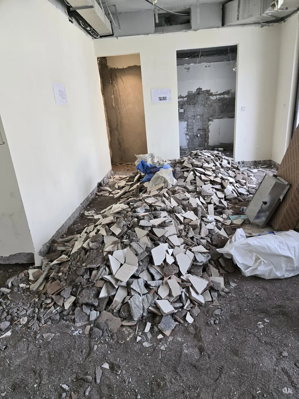 The two square openings to the pantry and kitchen during strip-out, before they were formed into arches, with broken tiles on the floor