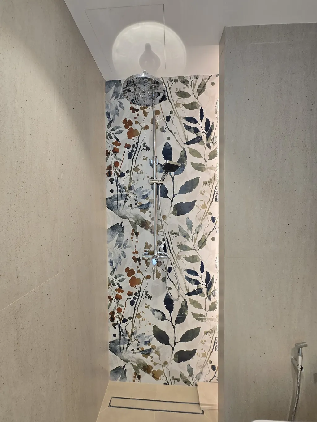 Shower wall in a botanical-pattern feature tile beside a wall-hung WC